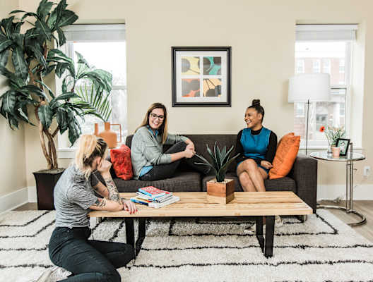 Three people are sitting on a couch in a living room.