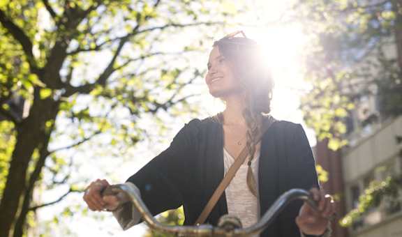 A woman is riding a bike in a sunny park.