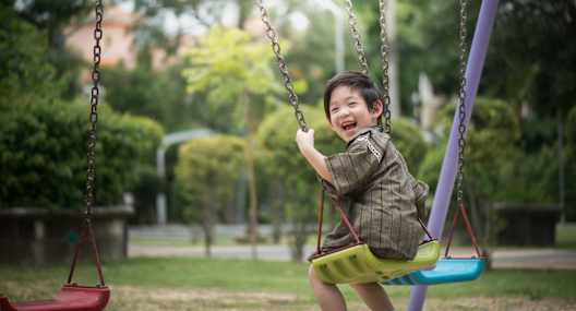 A young boy is swinging on a swing in a park.