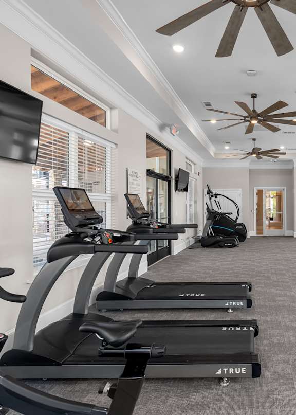 A gym with treadmills and a fan.