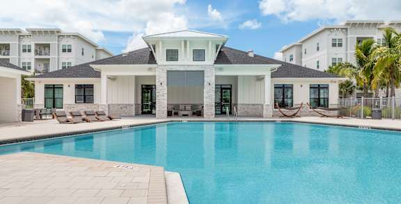 A palm tree stands in front of a pool at a resort.