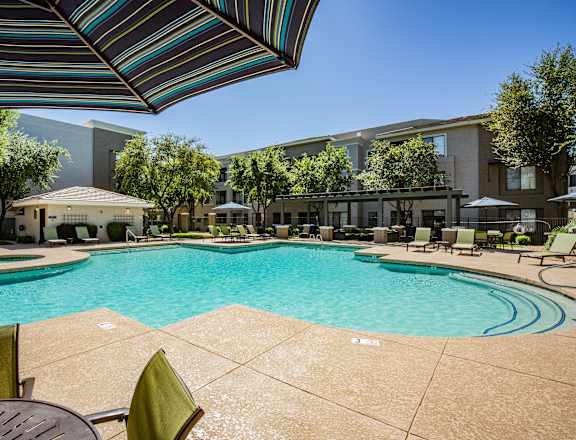 A large swimming pool surrounded by lounge chairs and umbrellas.