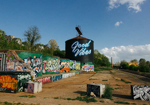 A wall covered in graffiti with a sign that says Good Vibes.
