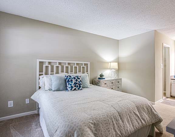 a bedroom with a large bed and a kitchen in the background