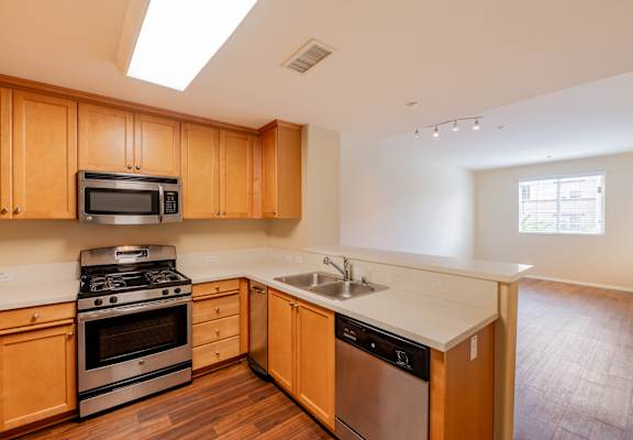 A kitchen with wooden cabinets and stainless steel appliances. at  Ventana Senior Apartments, Porter Ranch ,91326