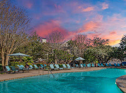 A large swimming pool surrounded by trees and lounge chairs.