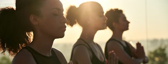 Three people are sitting cross-legged and meditating.