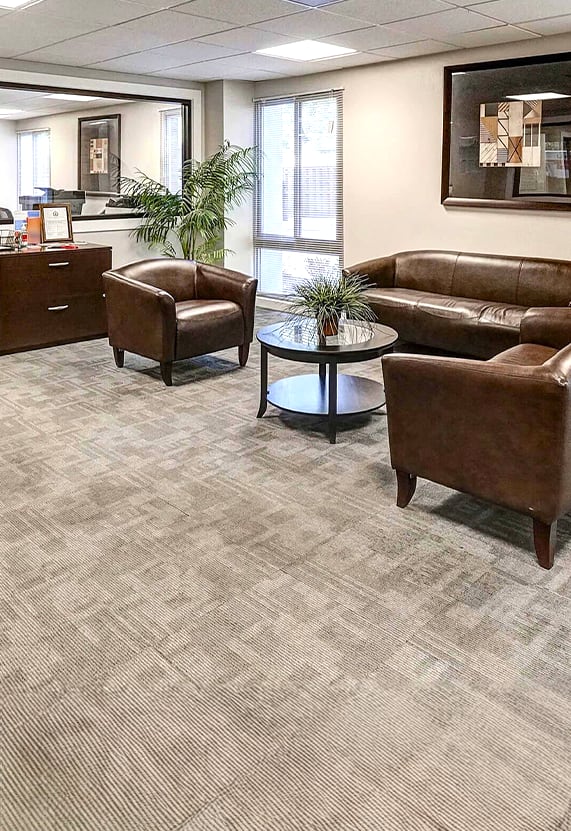 A spacious office room with a carpeted floor and a ceiling with a light fixture.