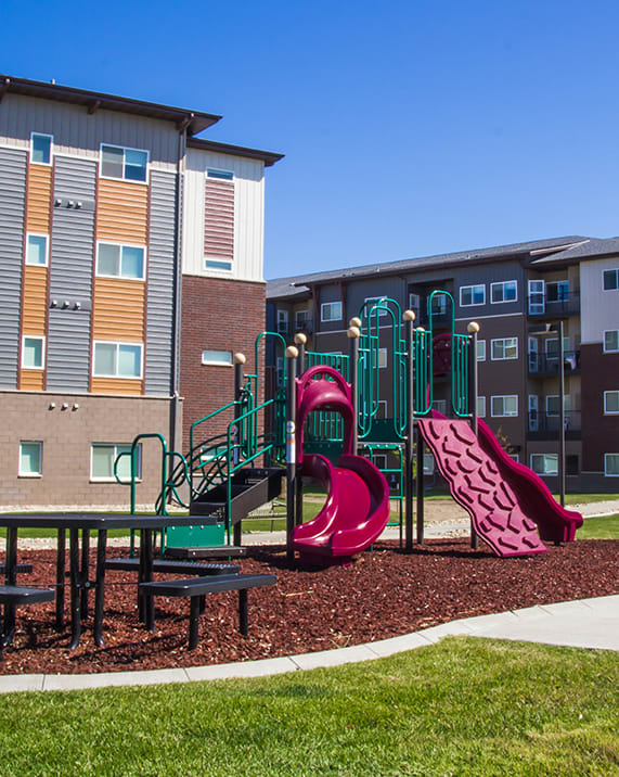 a playground with a pink slide in front of an apartment building