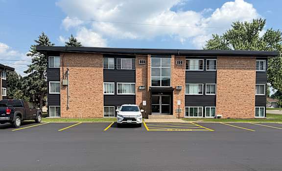 A parking lot in front of a multi-story apartment building.