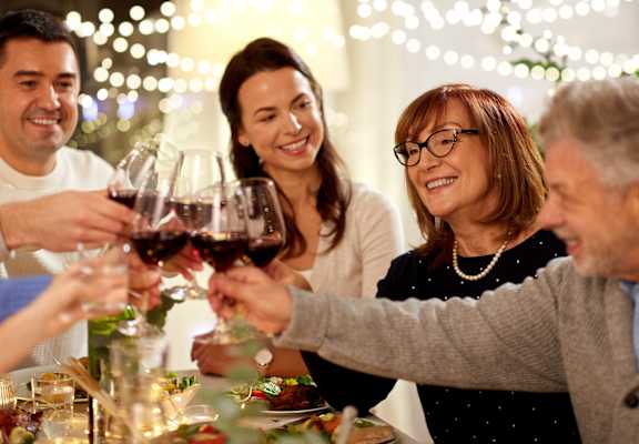 A group of people toasting with wine glasses at a festive gathering.