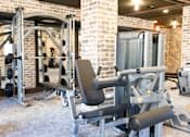 Thumbnail 8 of 9 - A gym with a variety of equipment including a leg press machine. at District on the Etowah Apartments, Canton, 30114