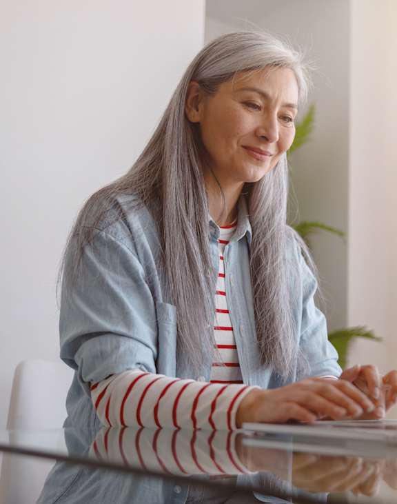 A woman with grey hair is using a laptop.