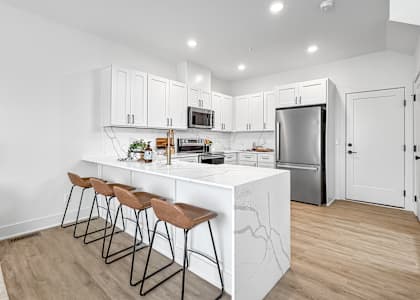 A kitchen with white cabinets and a marble island.