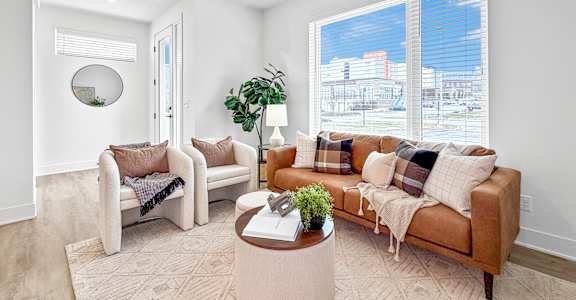 A living room with a couch, chair, and potted plant.