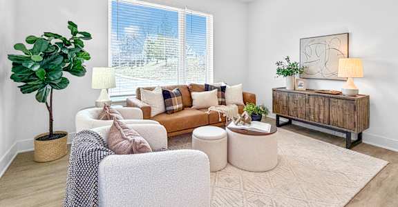 A living room with a couch, chair, and potted plant.