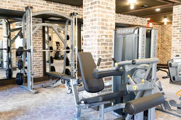 A gym with a variety of equipment including a leg press machine. at District on the Etowah Apartments, Canton, 30114