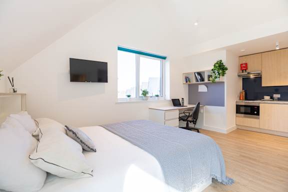 A bedroom with a bed, desk, and chair.