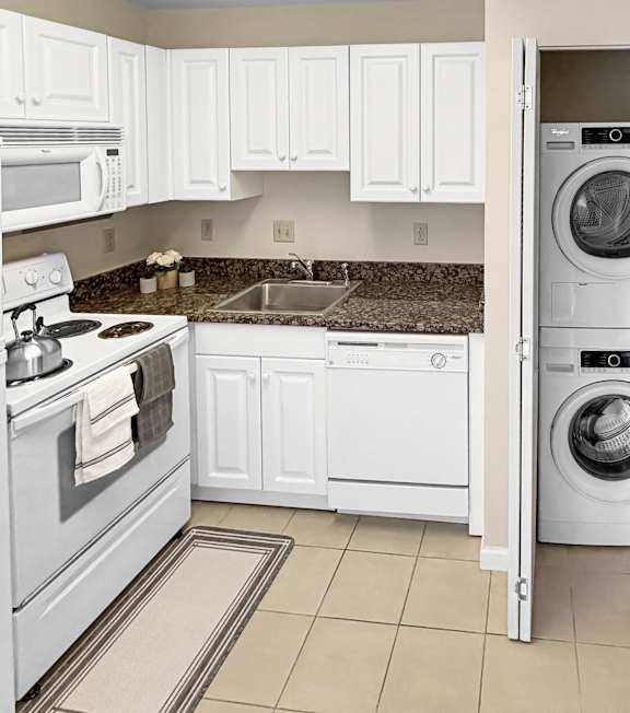 A white kitchen with a refrigerator, microwave, oven, and washing machine.