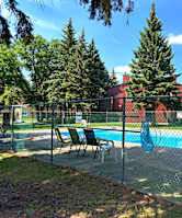 A pool surrounded by a fence with trees in the background.