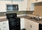 Thumbnail 34 of 48 - A modern kitchen with black and white appliances and wooden flooring.