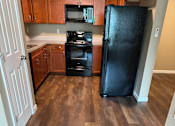 Thumbnail 42 of 48 - A kitchen with a black TV mounted above a white fridge.