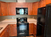Thumbnail 46 of 48 - A kitchen with wooden cabinets and a black countertop.