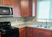 Thumbnail 29 of 48 - A kitchen with wooden cabinets and black appliances.