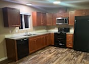 Thumbnail 22 of 48 - A kitchen with wooden cabinets and a black countertop.