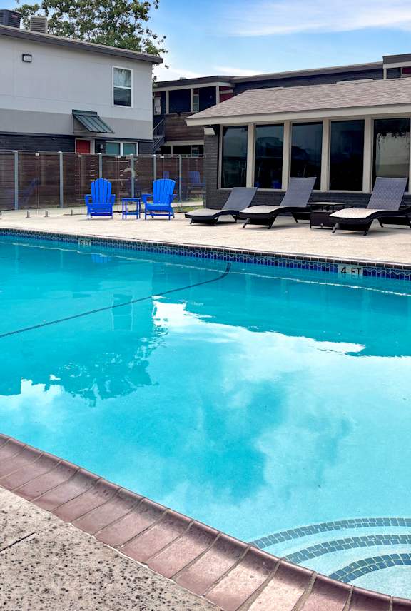A swimming pool with blue chairs around it.