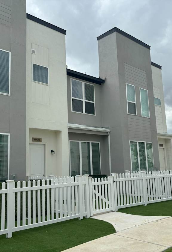 A white picket fence in front of a modern two-story house.