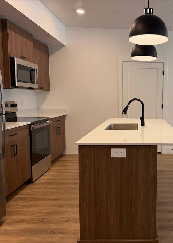 A kitchen with a white countertop and wooden cabinets.