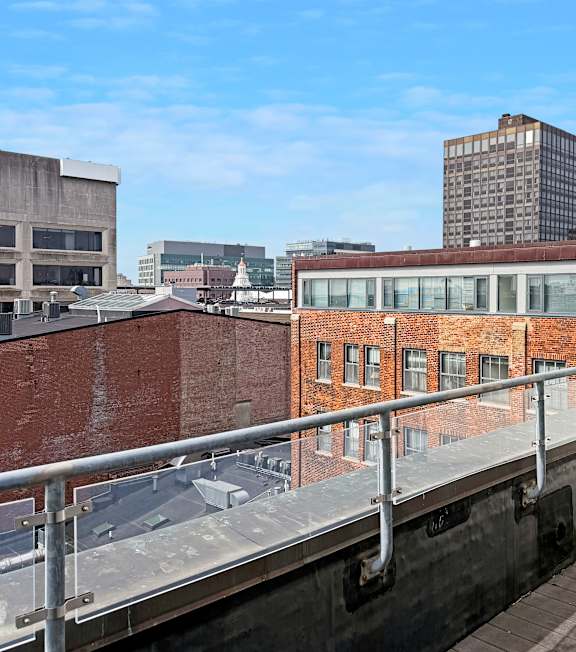 A balcony with a metal railing overlooks a cityscape.