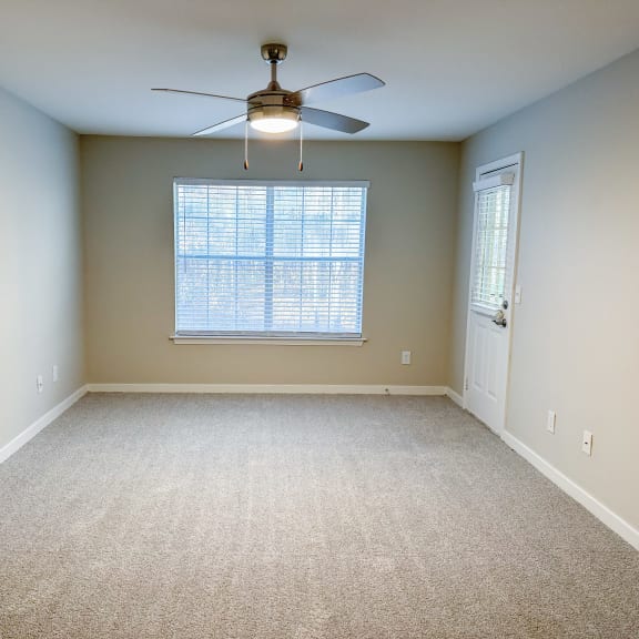 an empty living room with a ceiling fan and a window