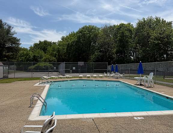 A large outdoor swimming pool surrounded by a fence and trees.