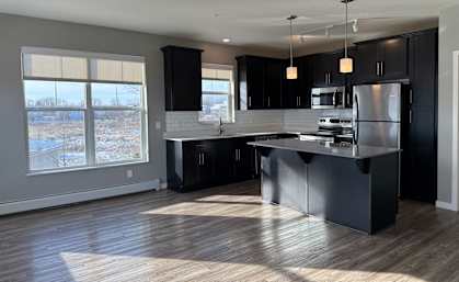 A modern kitchen with black cabinets and a large island.