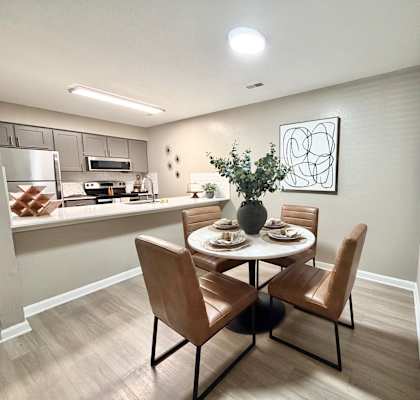 A dining room with a table set for two and a kitchen area in the background.