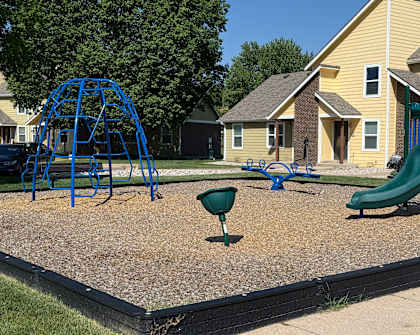 A playground with a blue swing set and a green slide.