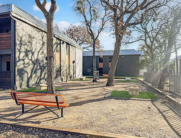 A bench is in the foreground of a yard with a building in the background.