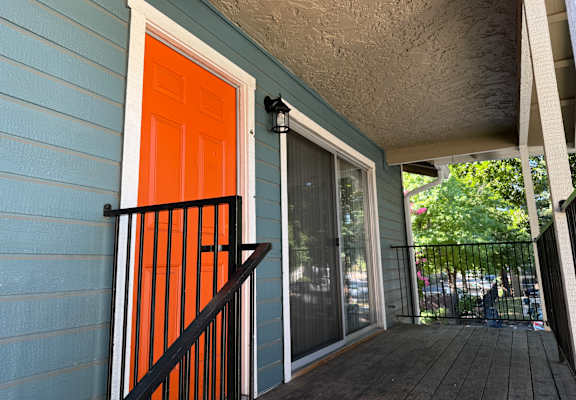 A blue house with a red door and a black railing.