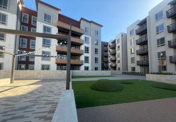 A modern apartment complex with a well-maintained lawn and walkway.