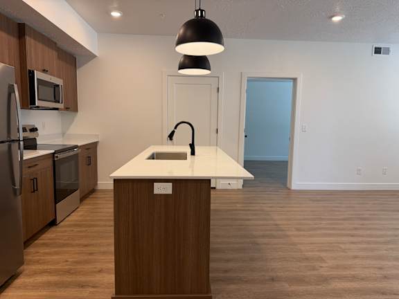 A kitchen with a white countertop and wooden cabinets.