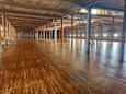 A large, empty warehouse with wooden floors and exposed beams.