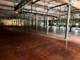 A large, empty warehouse with wooden floors and green metal beams.