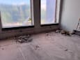 A room with a large window and debris on the floor.