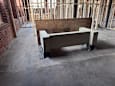 A concrete bench with a brown cushion is in the middle of a construction site.