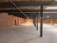 A large, empty warehouse with a concrete floor and brick walls.