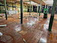 A large room with wooden floors and green pillars.