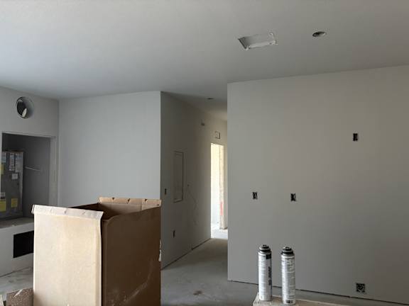 A room with a white ceiling and walls, a cardboard box, and two spray cans on the floor.