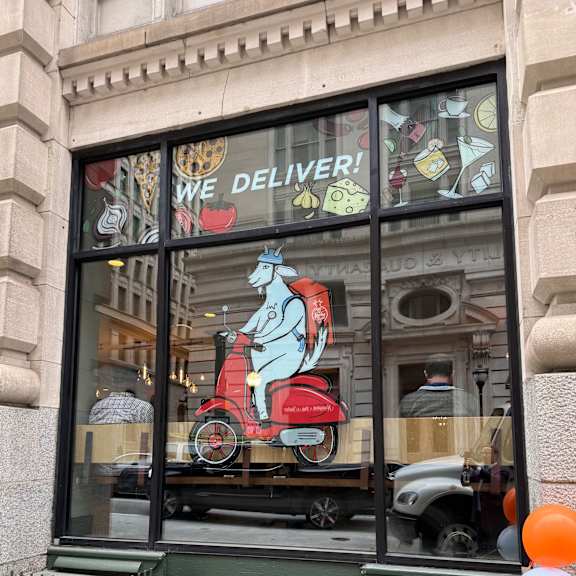 the window of a restaurant with a window display of a red car and balloons